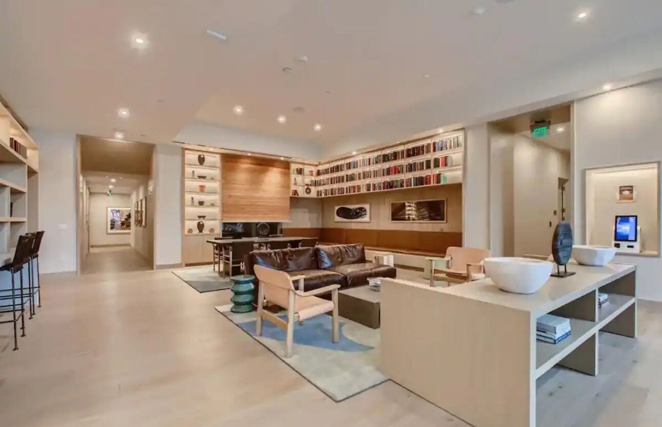 Un salon moderne avec un canapé, une table basse et une bibliothèque remplie de livres.