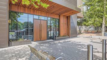Un bâtiment moderne avec une façade en bois, de grandes portes vitrées et un banc à l’extérieur.