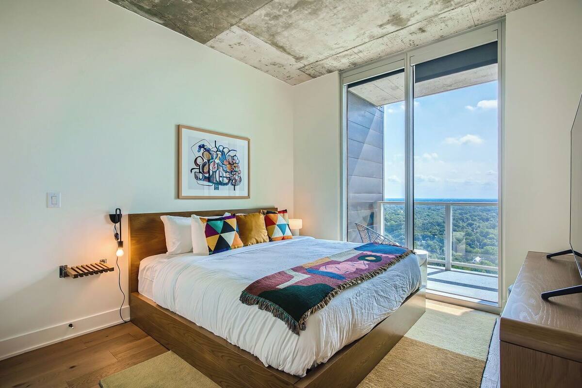 Un dormitorio con una cama grande, vistas al exterior y techo de madera.