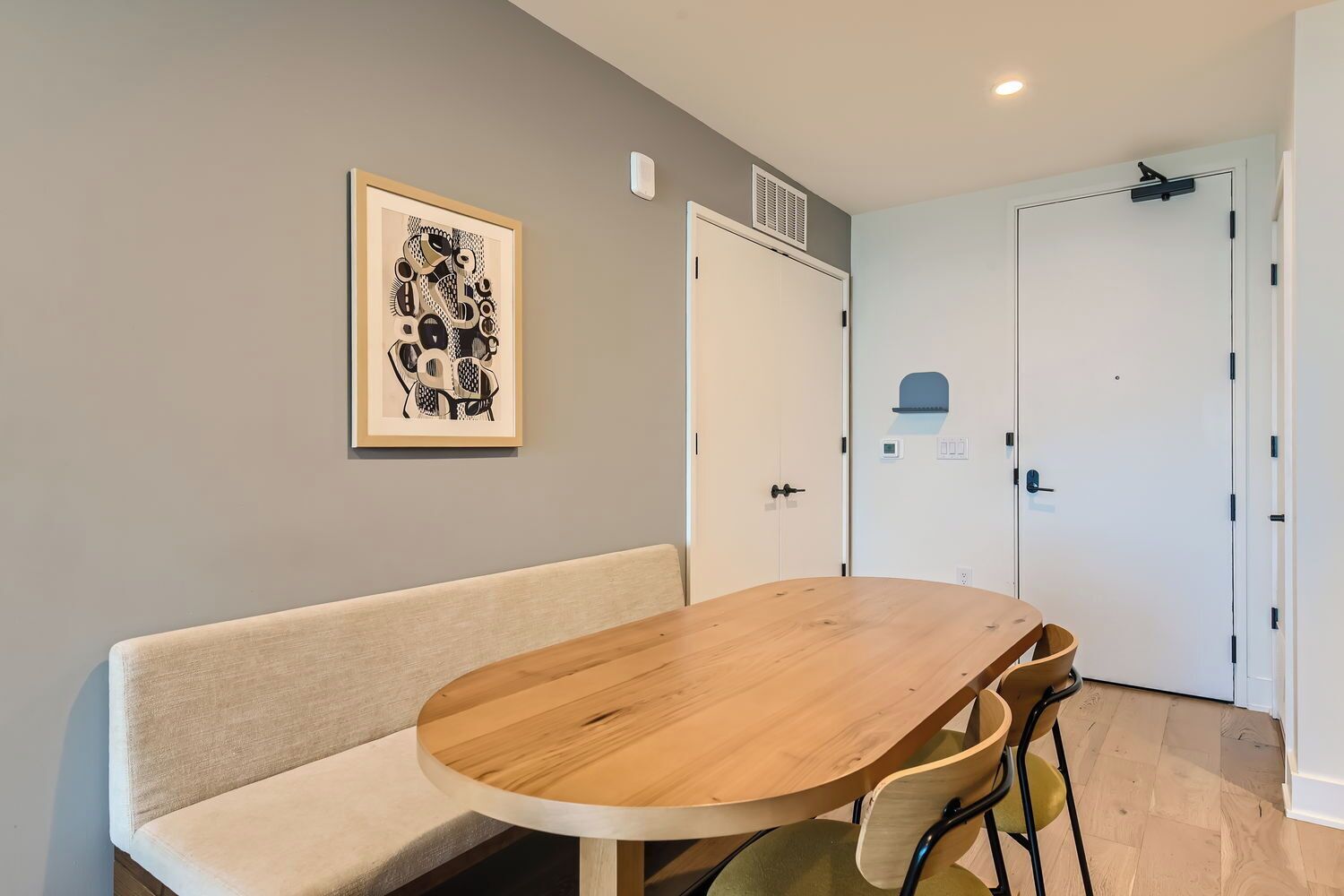 Una habitación con una mesa redonda de madera, un sofá color beige y una obra de arte abstracto enmarcada en la pared.