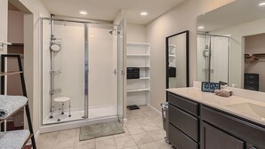A modern bathroom with a glass-enclosed shower, a vanity with a mirror, and built-in shelves. - Serene 3 Br Retreat Near East Austin (Austin)