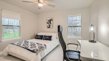 A bedroom with a bed, a desk, a chair, and a ceiling fan.