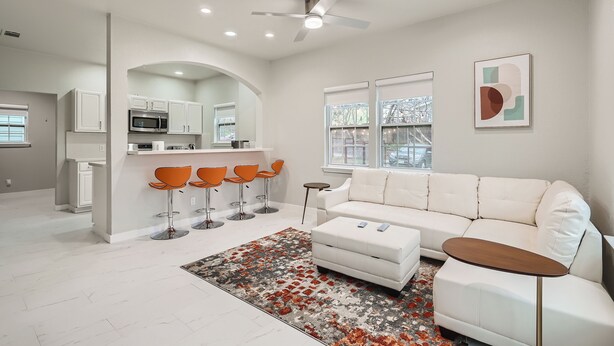 A modern living room with a white sofa, orange bar stools, and a coffee table. - Chic Retreats In Central East Austin (Large Groups) (Austin)