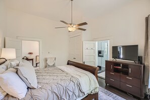 Relax in a spacious bedroom with a large bed, tufted headboard, and flat-screen TV.