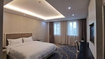 Quarto de hotel moderno com uma cama grande, uma escrivaninha e uma televisão.