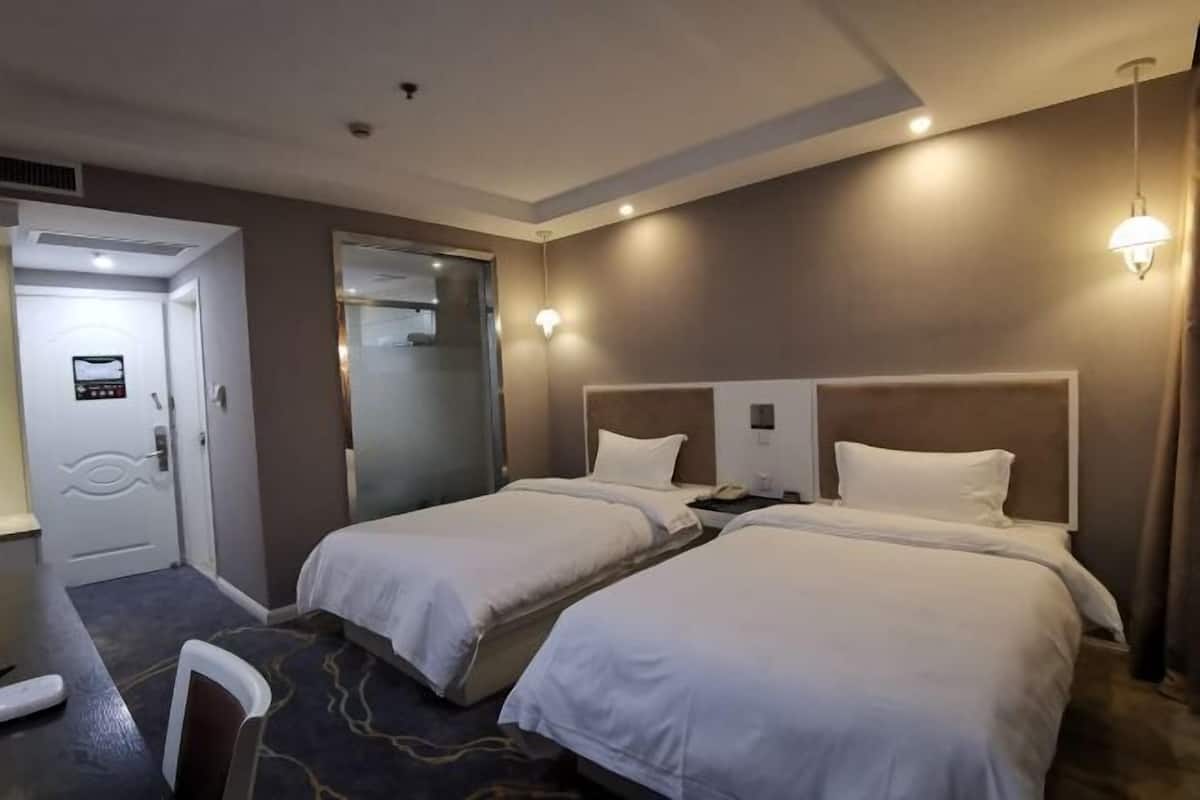 Habitación de hotel con dos camas, un escritorio y una silla.