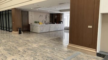 A hotel lobby with a reception desk, a wooden door, and a marble floor.