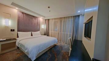 A hotel room with a bed, a desk, a chair, a TV, and a window with curtains.
