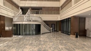 A spacious lobby with a marble floor, a central staircase, and a high ceiling. - Xinshan Hotel (Xinchang)
