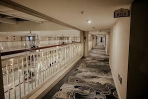 A hotel corridor with a patterned carpet, glass railings, and a sign indicating room number 8416. - Xinshan Hotel (Xinchang)