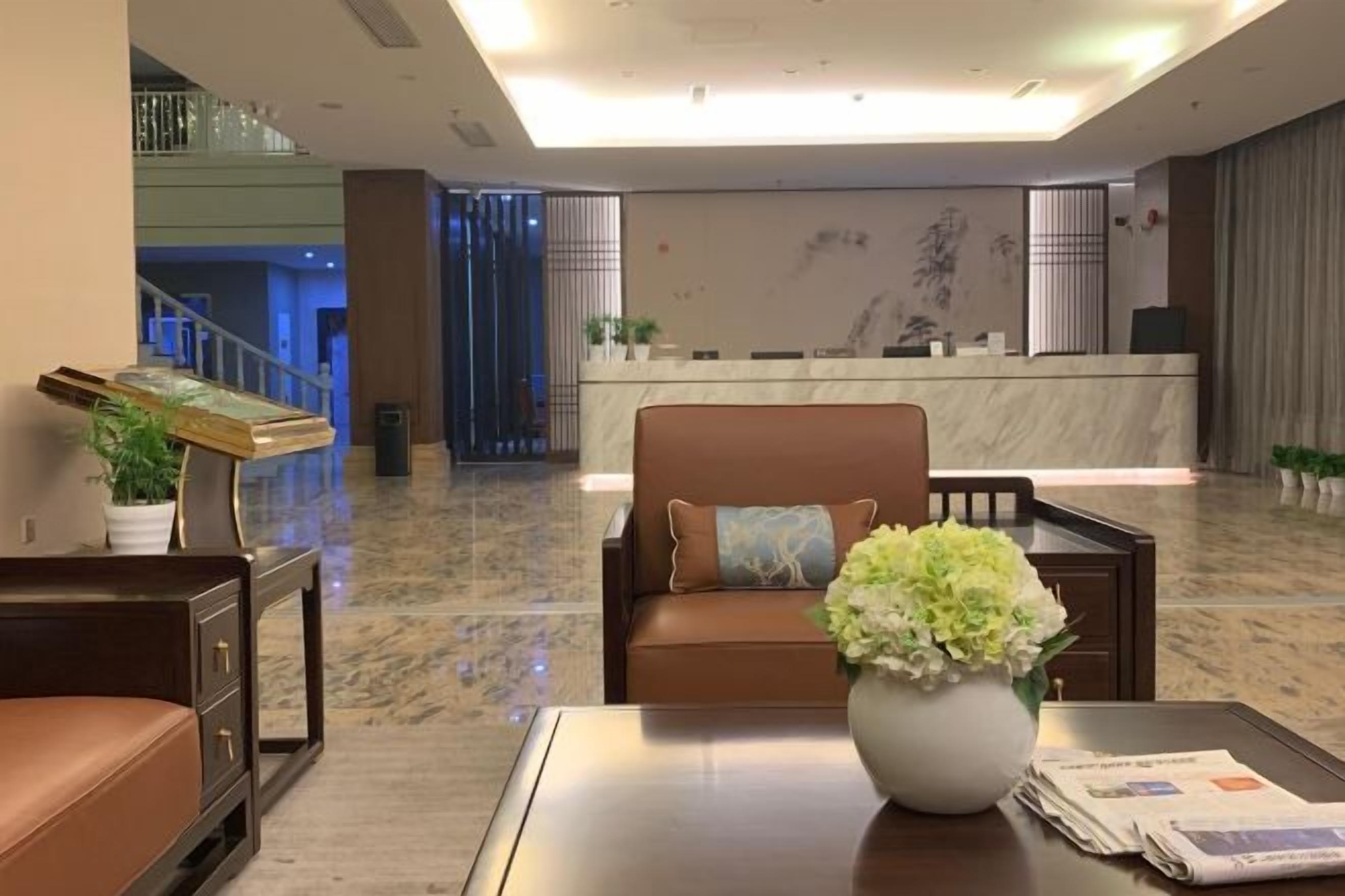 A hotel lobby with a reception desk, seating area, and a staircase.