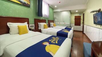A hotel room with four beds, each with a blue and yellow bedspread, white pillows, and a painting on the wall.