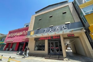 Un edificio con un letrero que indica '7天酒店', señalando un hotel. Hay una fachada con toldo rojo y un letrero que dice '餐厅', que significa restaurante.