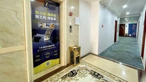 A hotel lobby with a marble floor, a patterned rug, and a poster advertising a 7-day hotel stay.
