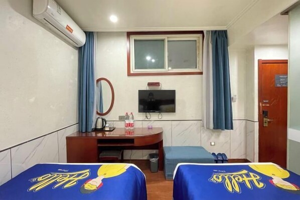 Una habitación de hotel con dos camas, televisión, escritorio y ventana con cortinas.