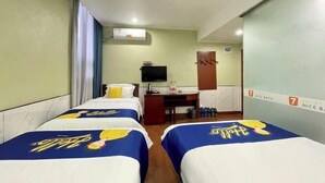 A hotel room with two beds, a desk, a television, and a bathroom door.