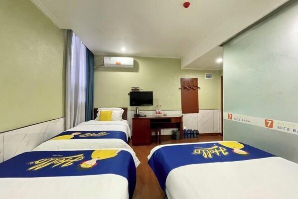 Habitación de hotel con dos camas, un escritorio, un televisor y la puerta del baño.