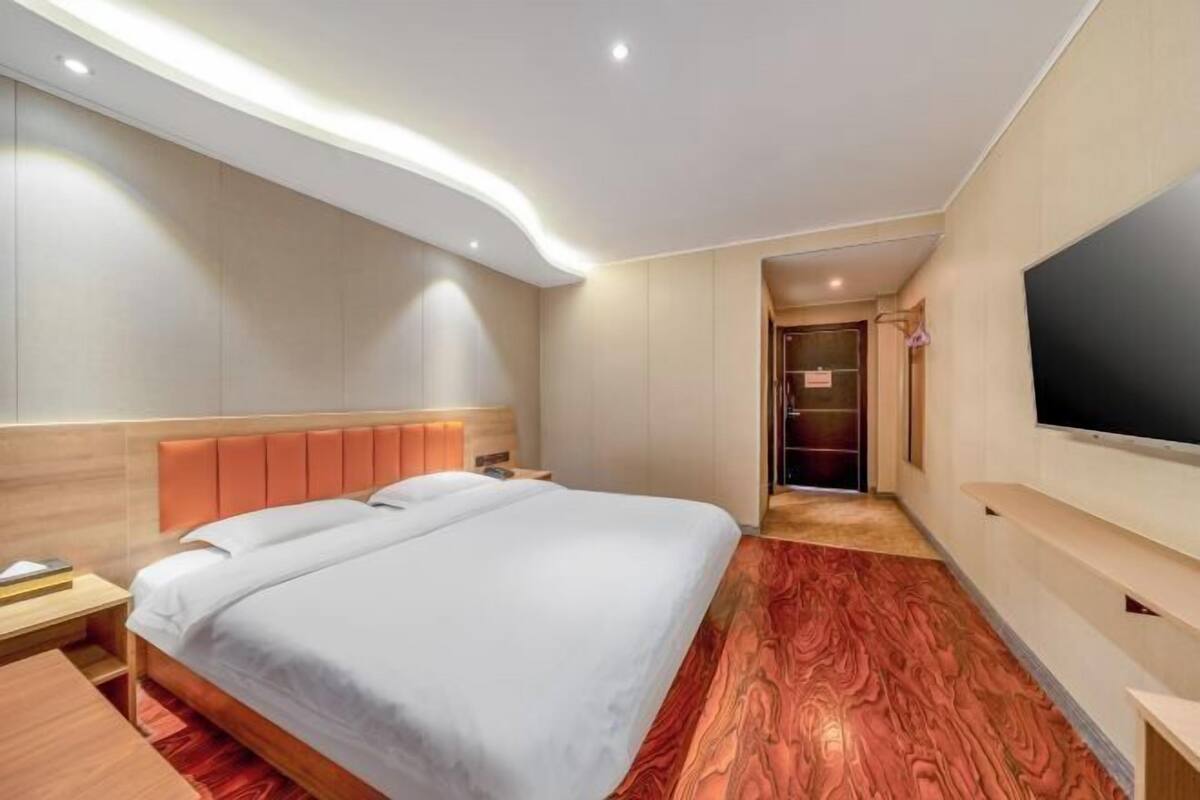 Ein modernes Hotelzimmer mit einem großen Bett, einem Flachbildfernseher und Holzboden.