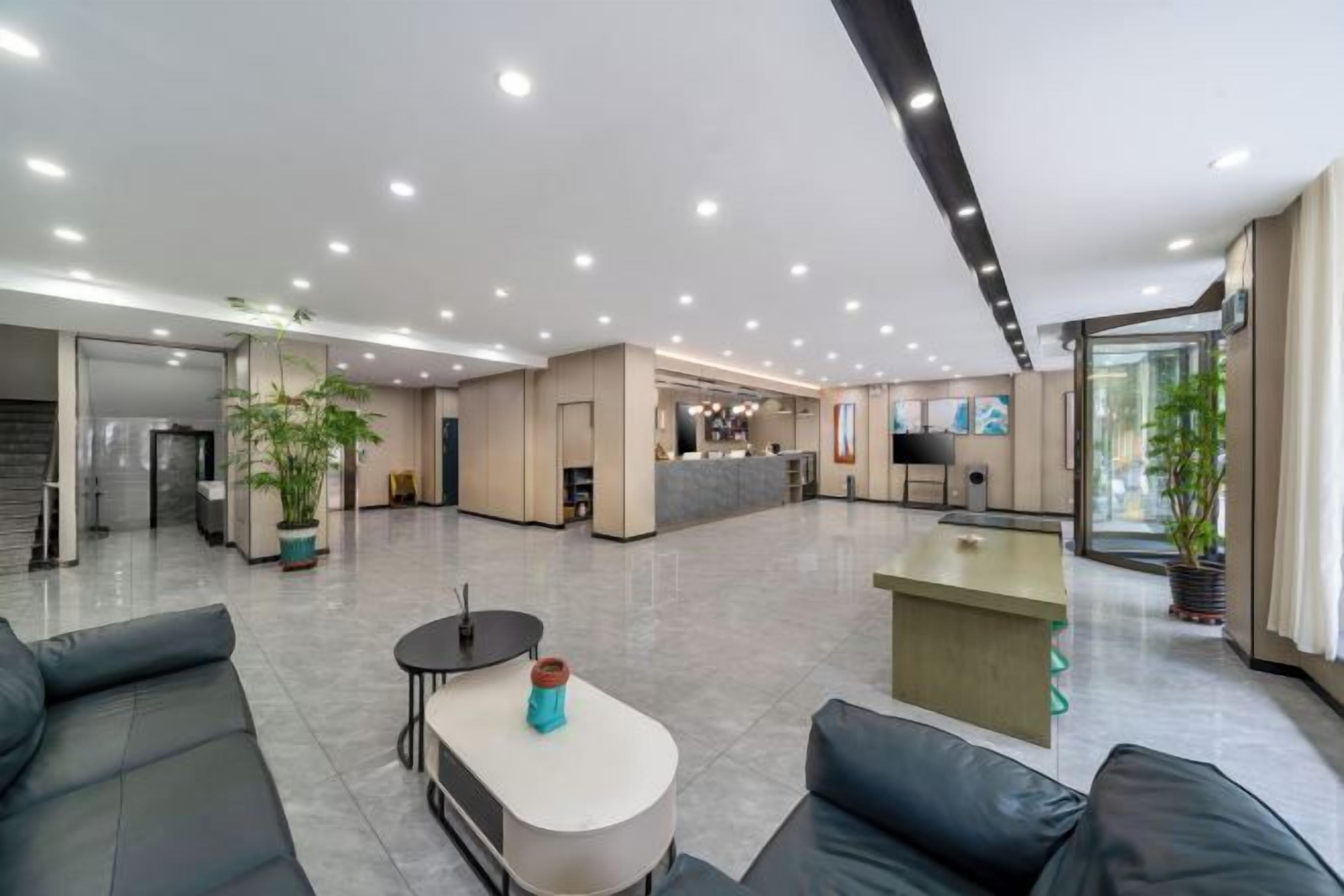 A spacious hotel lobby with a reception desk, seating area, and a kitchen in the background.