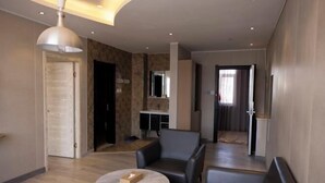 En moderne hotellobby med siddeområde, reception og et stort spejl.