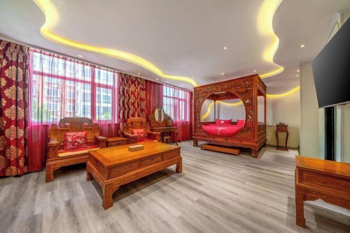 Ein traditionell eingerichtetes Schlafzimmer mit Himmelbett, Holzmöbeln und einem großen Fenster mit Vorhängen.