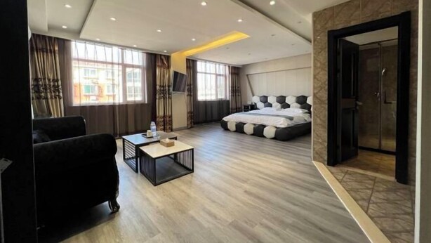 Et moderne hotelværelse med en stor seng, en sofa, et lille bord og et badeværelse med bruser og toilet.