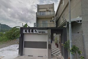 Un edificio con puerta de garaje, un balcón y pavimento a cuadros.