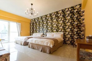 Habitación de hotel con dos camas, una araña, papel tapiz floral y vistas al exterior.