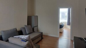 Un salon avec un canapé gris, un téléviseur à écran plat et un plancher en bois.