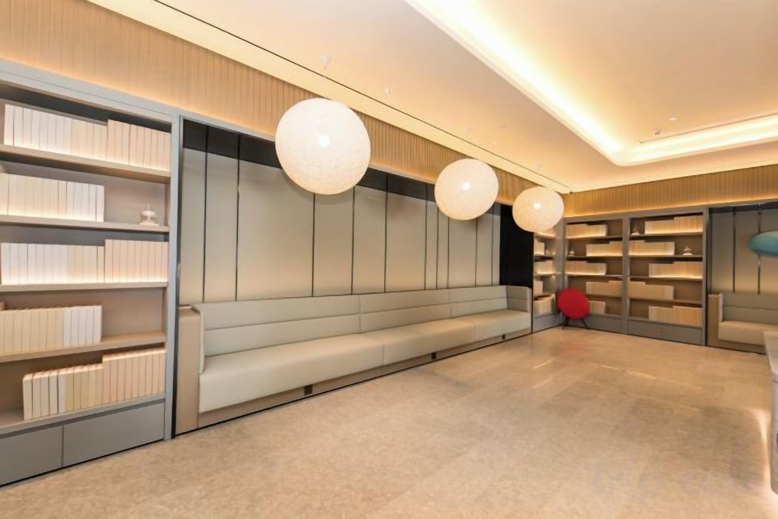 A modern interior with a long bench, bookshelves, and pendant lighting.