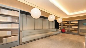 A modern library with built-in bookshelves, a long bench, and spherical pendant lights. - JI Hotel (Huzhou Dongwu Intime City Renhuangshan Store) (Huzhou)