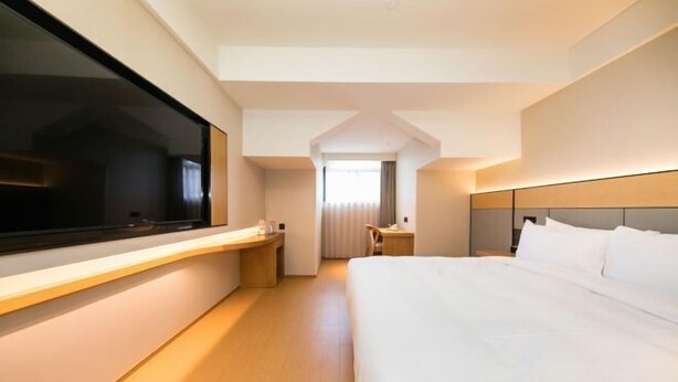 A modern hotel room with a large bed, a desk, and a TV. - JI Hotel (Huzhou Dongwu Intime City Renhuangshan Store) (Huzhou)