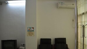 Une salle d’attente avec deux chaises, une petite table avec un téléphone et un appareil de climatisation fixé au mur.