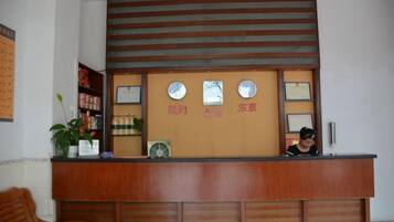 A reception desk with a wooden finish, a plant on the left, and framed certificates on the wall.