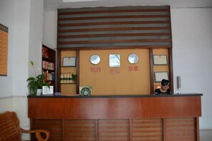 Una recepción con detalles de madera, una planta a la izquierda y diplomas enmarcados en la pared.