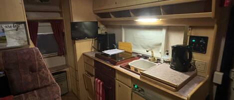 A compact kitchenette with a sink, stove, and a small refrigerator.