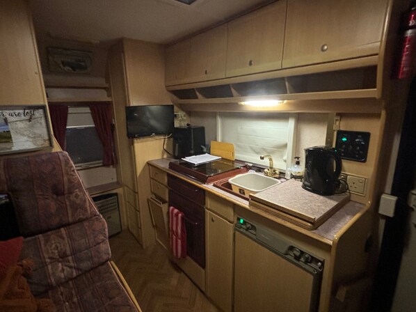 A compact kitchenette with a sink, stove, and a small refrigerator. - Motorhome in Hinckley- Sleeps 3- Pet Friendly (Hinckley)