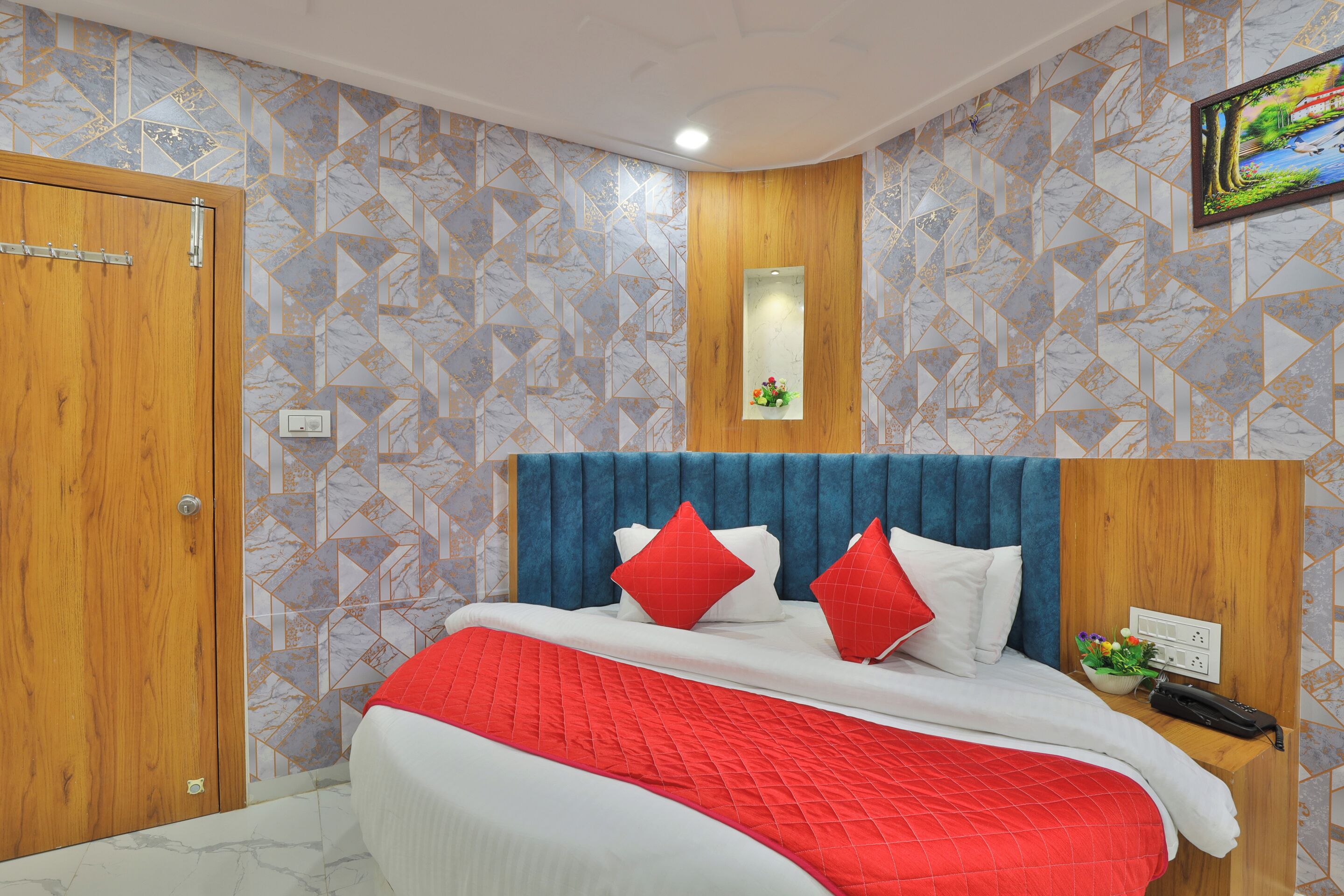 A hotel room with a bed, wooden wardrobe, and a wall-mounted TV.