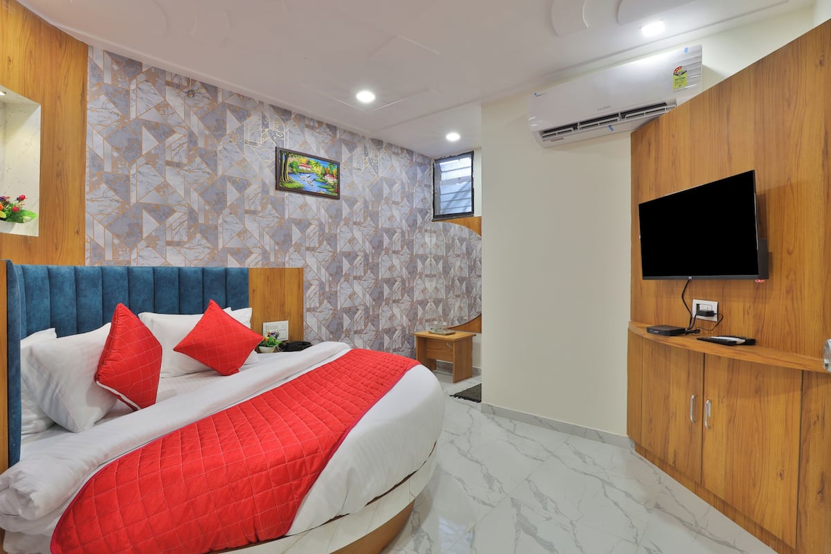 A modern hotel room with a large bed, a TV mounted on the wall, and a wooden wardrobe.
