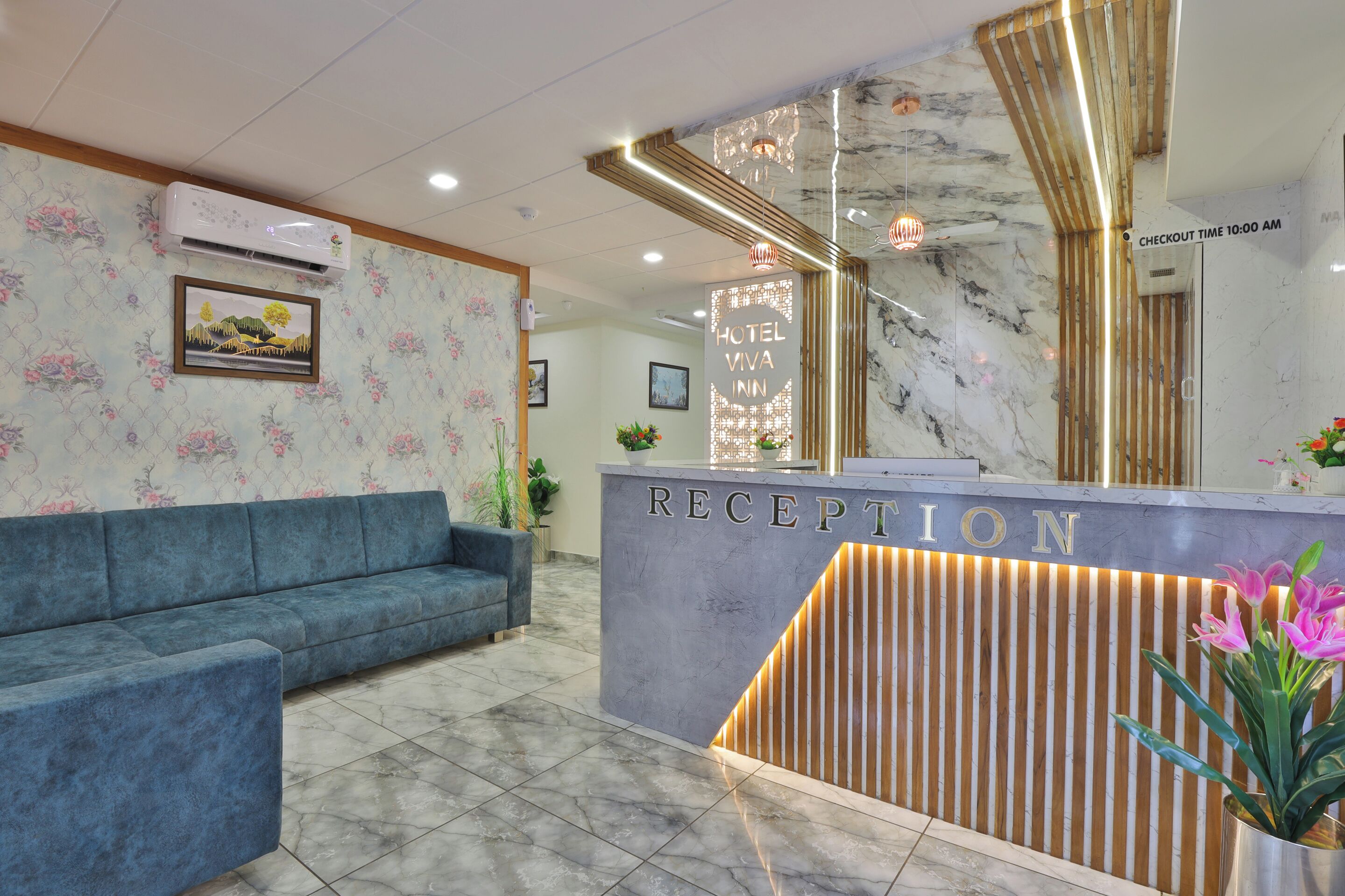 A hotel reception area with a marble reception desk, a blue sofa, and a check-in sign.