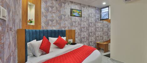 A modern bedroom with a large bed, a wooden headboard, and a geometric patterned wall.