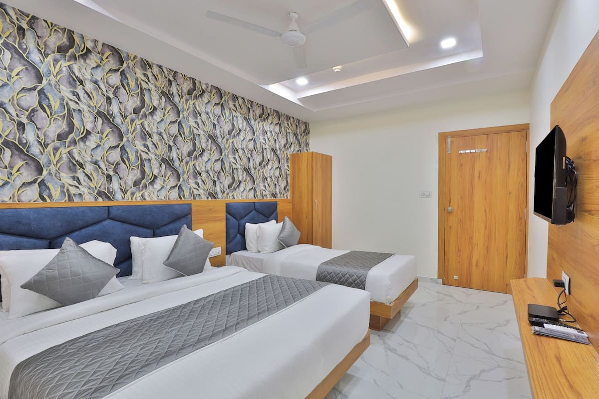 A hotel room with two beds, a wooden wardrobe, a television, and a patterned wall.