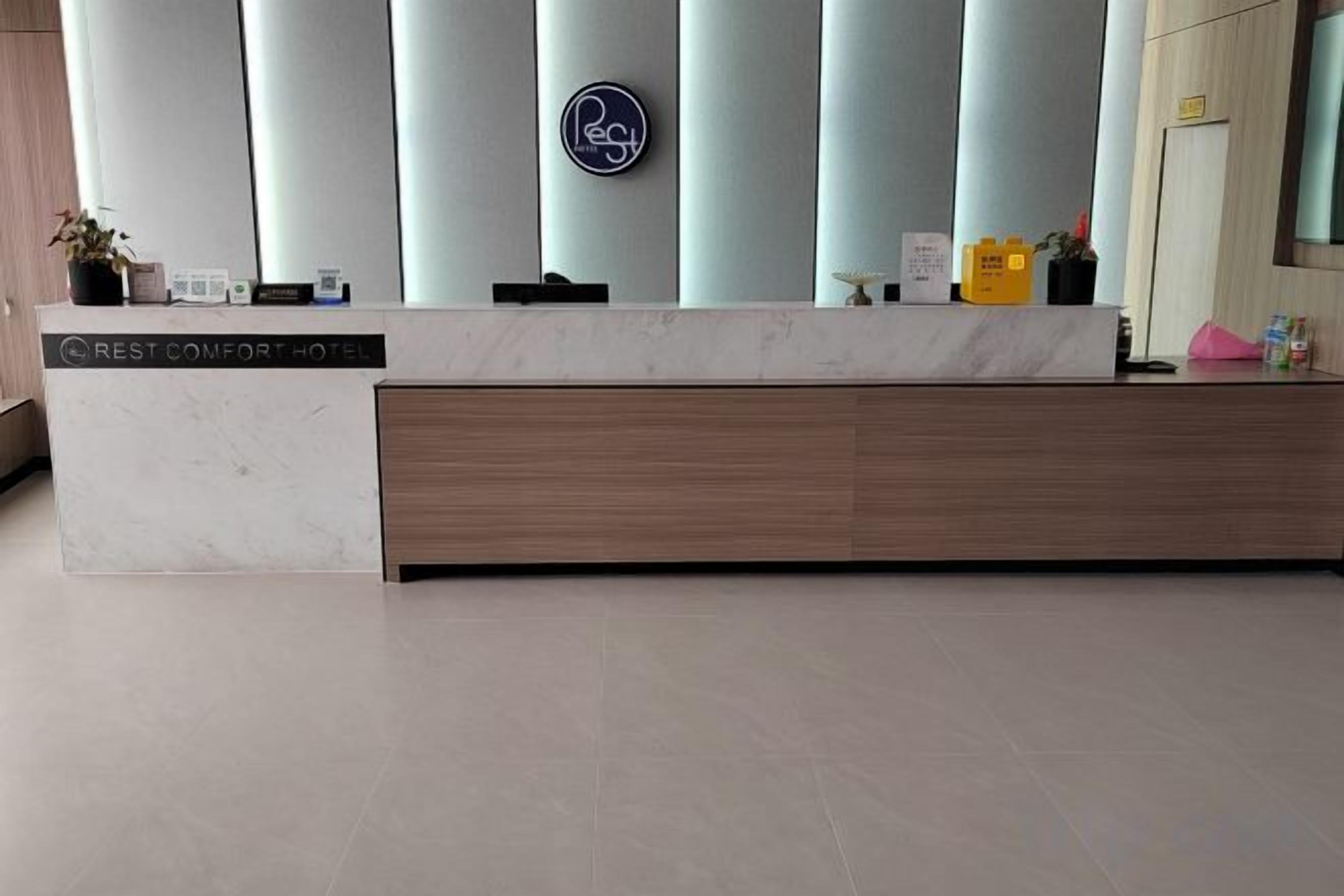A hotel reception desk with a marble top, a wooden panel, and a vertical sign with a logo.