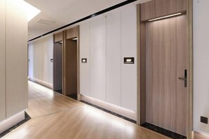 A hotel corridor with wooden flooring, a series of doors, and a light fixture on the ceiling. - Rest Yizhi Hotel (Wenzhou Dongtou Passenger Terminal) (Wenzhou)