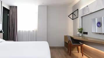 Quarto de hotel moderno com uma cama grande, uma escrivaninha com cadeira, uma TV de tela plana na parede e uma janela com cortinas.