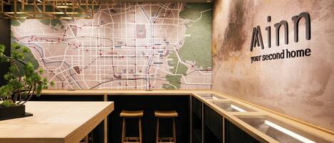A modern interior with a large map on the wall, wooden furniture, and a sign reading "Minn your second home".