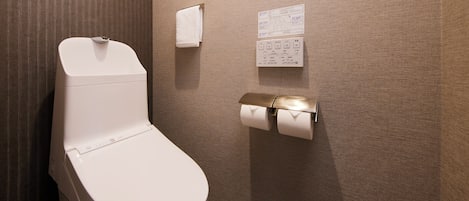 Uma casa de banho moderna com sanita, dispensador de toalhas e dispensador de papel.