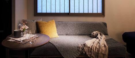 A cozy seating area with a sofa, a small round table, and a window with a view.