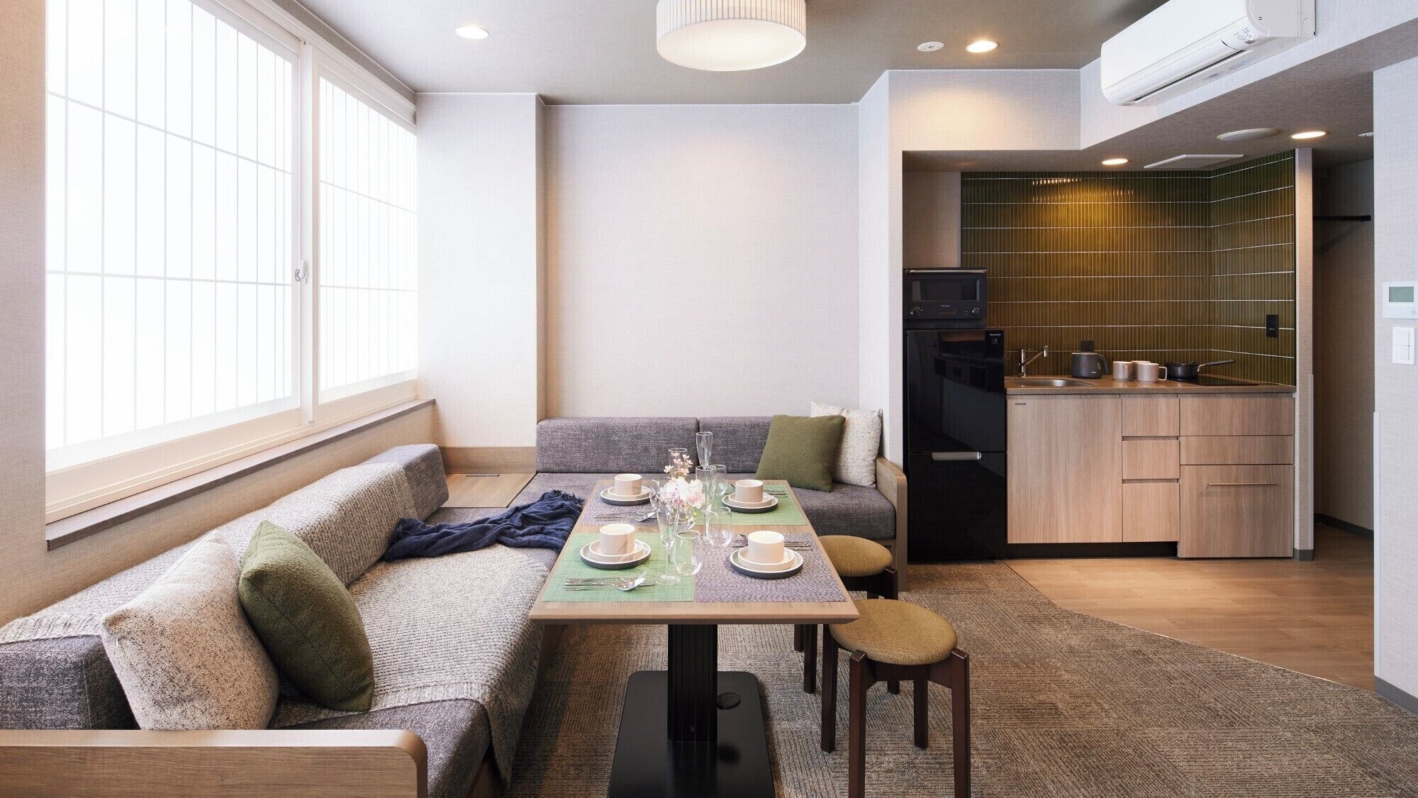 A modern living space with a sofa, dining table, and kitchen area.