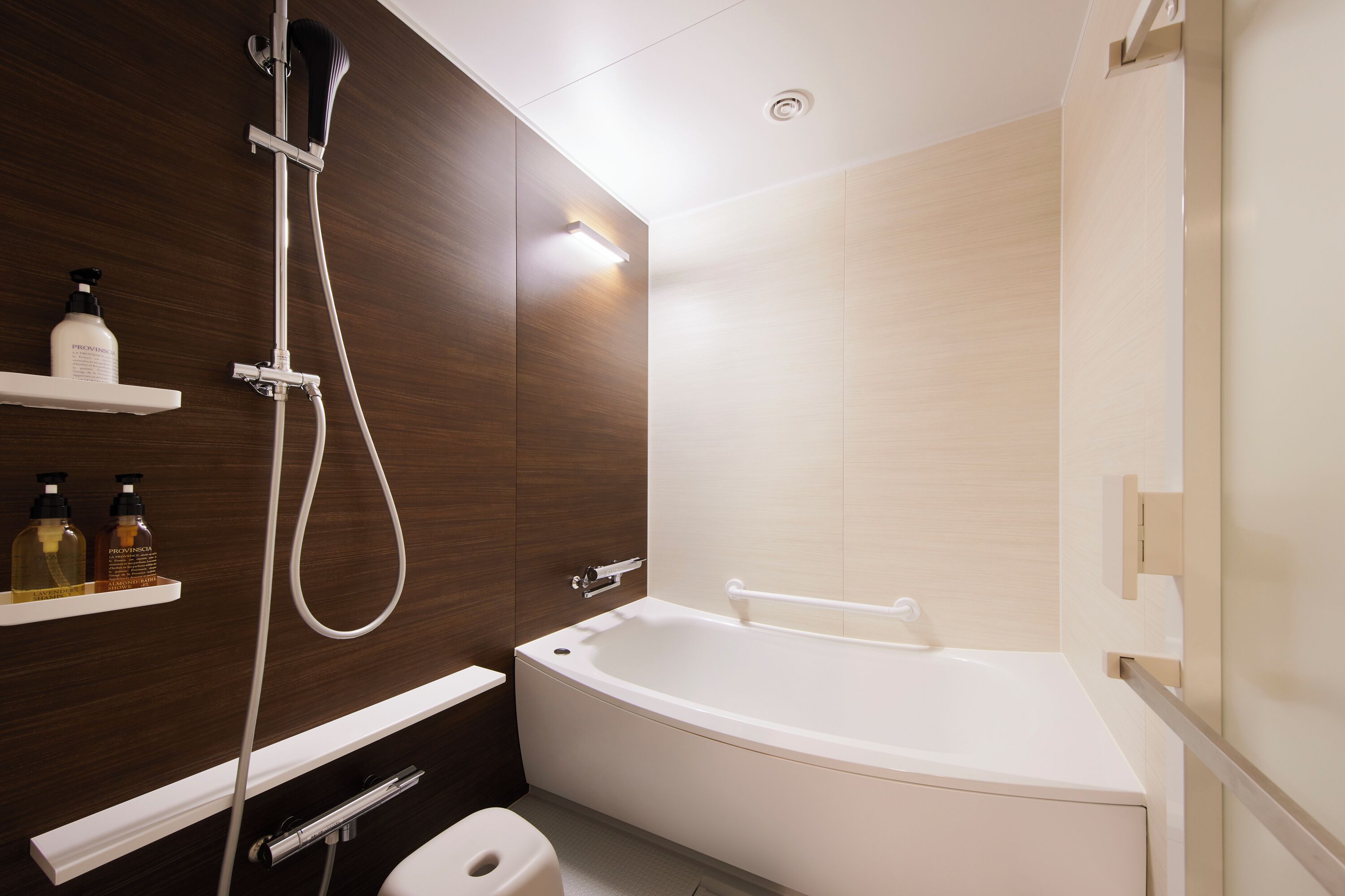 Een moderne badkamer met een badkuip, douche en toilet. Er staan planken met toiletartikelen op.